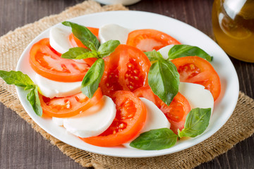 Close-up photo of caprese salad with ripe tomatoes, basil, buffalo mozzarella cheese. Italian and Mediterranean food concept. Fresh and healthy organic meal. Starter and antipasti. 
