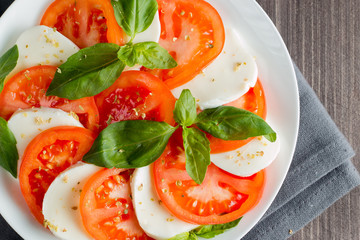 Close-up photo of caprese salad with ripe tomatoes, basil, buffalo mozzarella cheese. Italian and Mediterranean food concept. Fresh and healthy organic meal. Starter and antipasti. 