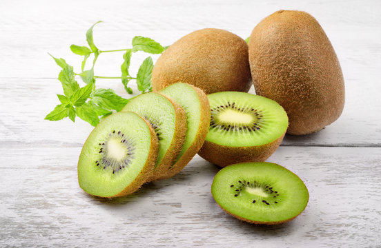 Green kiwi and mint leaves on white wood background