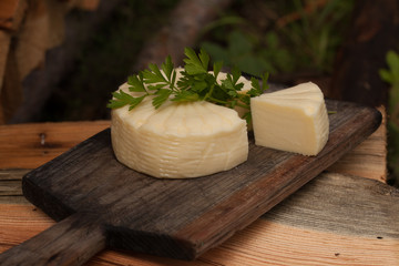 Wheel of brazilian traditional cheese Minas on wooden board. Selective focus