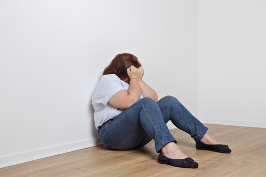 femme ronde pleurant contre un mur