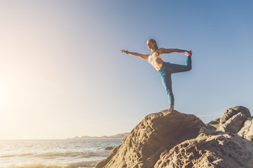 Woman doing yoga on the beach