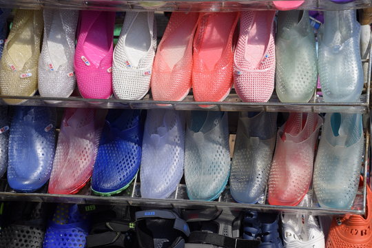 Rubber and silicone sandals and sneakers on the shoe shelf in the market.