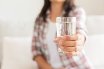 Happy beautiful young woman holding drinking water glass in her hand. Health care concept.