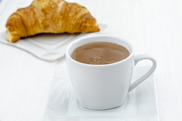 taza de chocolate caliente con un croissant 