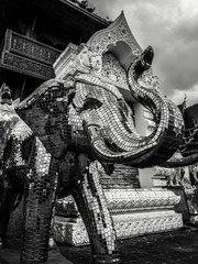 Modern buddhist sculpture of elephant covered with sparkling mirrors in dark and gloomy atmosphere with dramatic sky at Wat Banden, Thailand