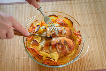 Baked chicken breast with potatoes, knife, fork, top view.