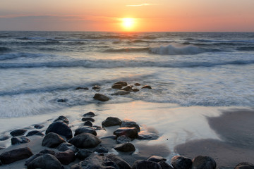 Fototapeta na wymiar Sunset evening beach overview with waves and wet stones. Danish coastline, Hirtshals in North Jutland in Denmark, Skagerrak, North Sea