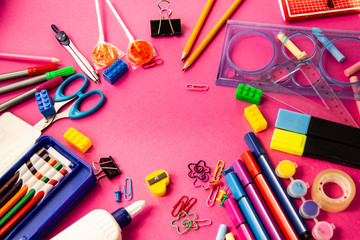 Felt pens, pencils, clips of different colors on a pink background