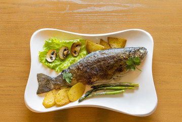Fried rainbow trout served with vegetables and greens
