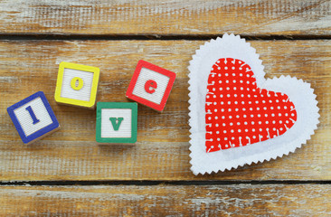 Wooden blocks with letters love and red knitted heart

