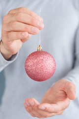 christmas balls. new year holiday decoration and festive ornaments concept. man holding rose gold glittery bauble