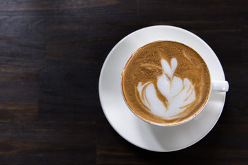 Latte art coffee cup with heart shape on wooden table, top view