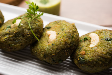 Hara bhara Kabab or Kebab is Indian vegetarian snack recipe served with green mint chutney over moody background. selective focus