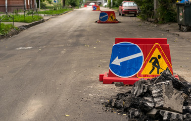 road sign, detour, road repair on the background of the road and broken asphalt pieces on the urban...