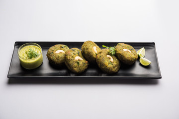 Hara bhara Kabab or Kebab is Indian vegetarian snack recipe served with green mint chutney over moody background. selective focus