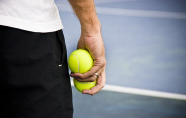Tennis player holding two yellow balls on the court.