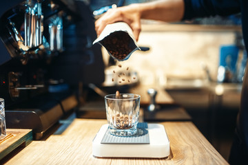 Barista hand pours coffee beans into the glass