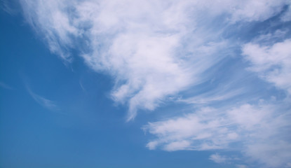 White curly clouds in a blue sky. Sky background