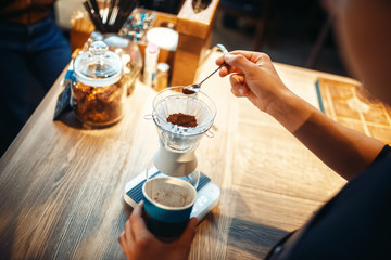 Male barista pours ground coffee into the glass