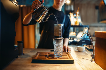 Barista pours water from coffee pot into the glass