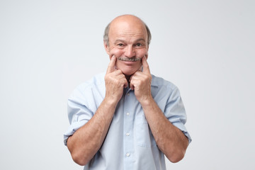 Handsome mature man in blue shirt trying to smile instead of bad depressed mood.