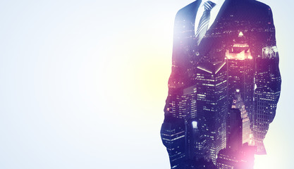 Young businessman thinking and standing with night skyscraper background