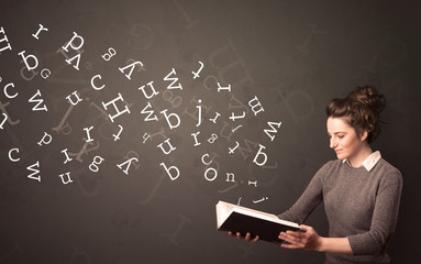 Casual young woman holding book with white alphabet flying out of it