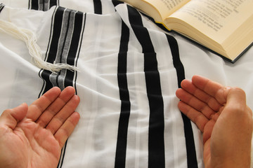 Jewish man hands next to Prayer book, praying, next to tallit. Jewish traditional symbols. Rosh...