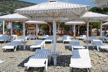 Sun loungers under a canopy. Infrastructure of the beach, protection from the sun