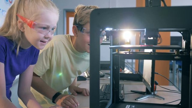 Kids working with 3D printer. Boy and girl working in a science laboratory with 3D printing equipment.
