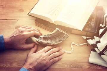 Jewish man hands next to Prayer book, praying, next to tallit. Jewish traditional symbols. Rosh...
