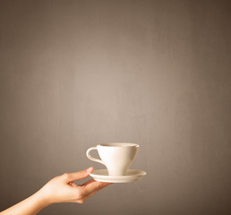 Young female hand holding coffee cup with brown background