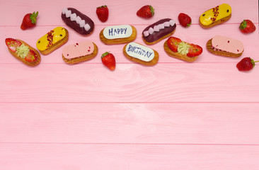 Happy birthday set of appetizing glazed eclairs on a pink wooden background