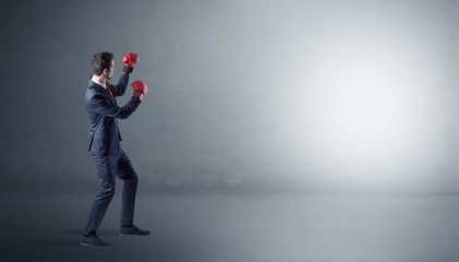 Businessman fighting with boxing gloves in an empty space
