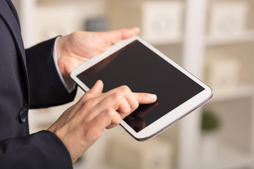 Business woman below chest using tablet in a homey environment
