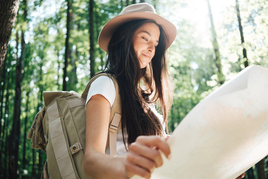Smiling breave girl with travel backpack, and location map in hands looking directional way for traveling on outdoors