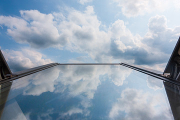 clouds reflected in roof window glass, tilted up against the sky