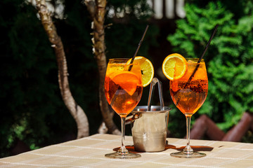 Aperol spritz cocktail glass plaid table leaves sun orange ice bucket shadow sunlight