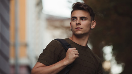 Handsome man in khaki color polo with bag over shoulder