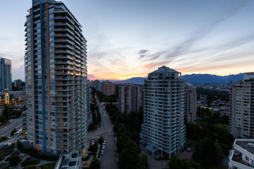 Obraz premium Metrotown, Burnaby, Vancouver, BC, Canada - June 26, 2018: Aerial view of Residential Homes near Metropolis Shopping Mall during a vibrant summer sunset.