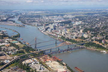 Obraz premium Aerial city view of Pattullo and Skytrain Bridge across the Fraser River. Taken in Greater Vancouver, British Columbia, Canada.
