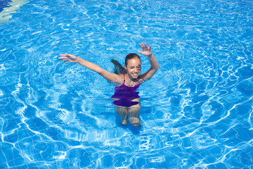 Smiling teenage girl swims in the outdoor pool