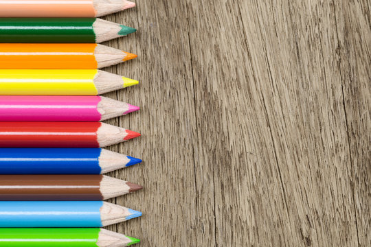 Top view of colorful color pencil stacked on wood background. Ideal for back to school, education and business abstract background concept.