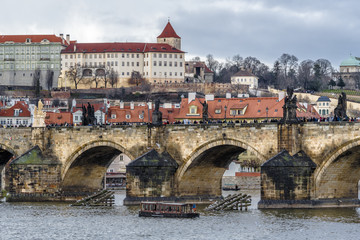 Obraz premium Semicircular arches of the Charles bridge on the background of the old quarters of Prague at the foot of the St. Vitus Cathedral.