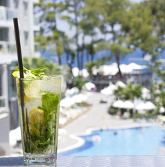 Mojito cocktail in glass on the background of the pool