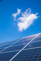 Group of solar panels against blue sky with clouds