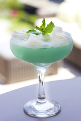 Blue cocktail in a beautiful glass with ice cream and green mint leaves