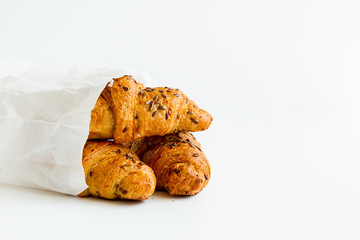 three delicious croissants in a white package on a white table