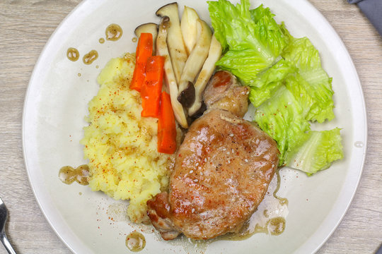 Pork steak with mashed potatoes and mushroom, green lettuce